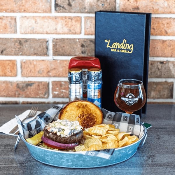 Gourmet burger with melted cheese, chips, and a glass of Kentucky Bourbon Barrel Ale.