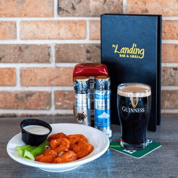A plate of buffalo wings with celery and ranch, a Guinness, and a "The Landing" menu.