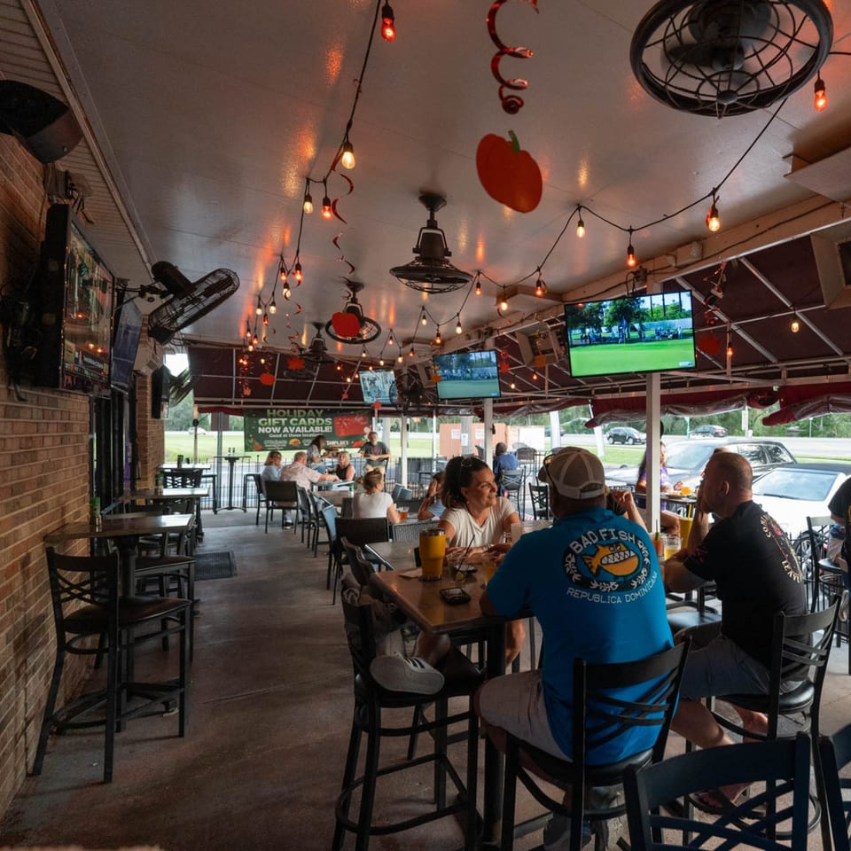 Patrons enjoying drinks and conversation on the outdoor patio of The Landing Bar and Grill.